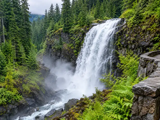 Narada Falls spilling over dark rock into a misty gorge